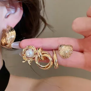 Elegant vintage gold metal earring set featuring heart and pearl designs on model