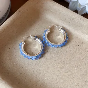 Close-up detail of elegant silver hoop earrings with sky blue crystal glass shards.