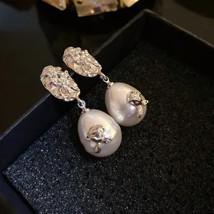 Close-up of French vintage pearl drop earrings with elegant silver flower details