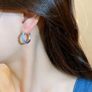 Detailed close-up shot of elegant minimalist blue glass hoop earrings on an Asian model