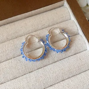 Detail view of silver hoop earrings decorated with sparkling light blue glass beads