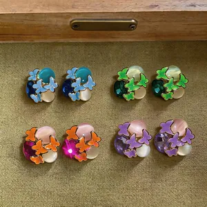 Detailed view of colorful butterfly earrings with rhinestones and cat's eye stones