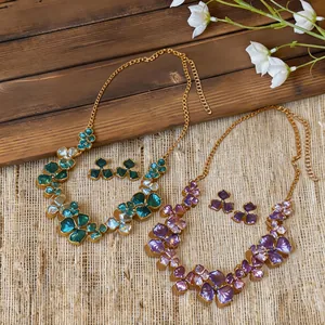 Detail shot of two French floral necklace and earring sets in green and purple colors.