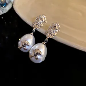 Close-up of French vintage pleated silver earrings with teardrop pearls and roses