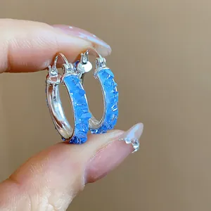 Close-up of elegant silver hoop earrings with sparkly blue crushed glass crystals.