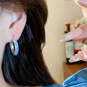 Close-up view of elegant Korean style glass hoop earrings in blue and silver finish