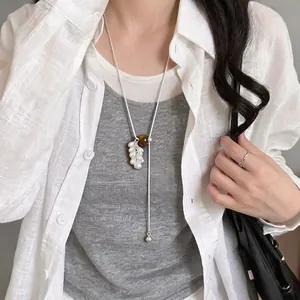 Long silver necklace with tiger eye stone and pearl grape bunch pendant on model