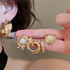 Close-up of a vintage golden metal earring set including textured heart and pearl designs