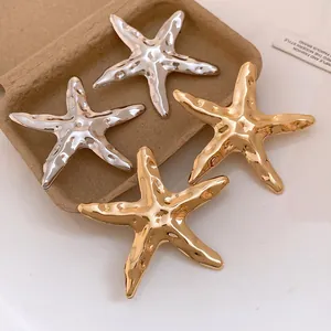 Detaillierte Ansicht von modischen Seestern-Ohrringen in Gold und Silber mit Metallstruktur.