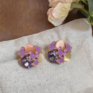Detail view of sweet forest style purple butterfly enamel earrings with faceted gemstones