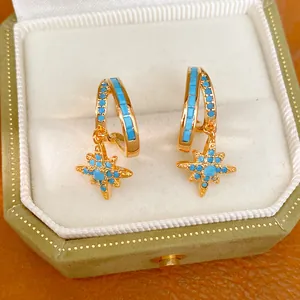 Macro detail of elegant gold star pendant earrings with vibrant blue turquoise inlay