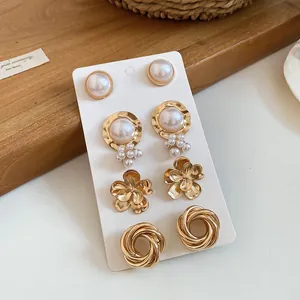 Close-up detail of a four-pair vintage gold-tone earring set featuring pearls and floral motifs