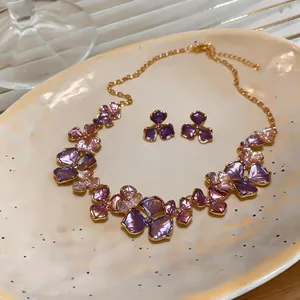 Detailed view of a French-style floral jewelry set with purple petals and gold chain.