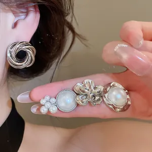 Close-up of elegant silver metal earring set with pearls and floral designs