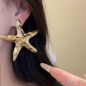 Detailansicht eines großen goldenen Seestern-Ohrrings mit strukturierter Oberfläche.