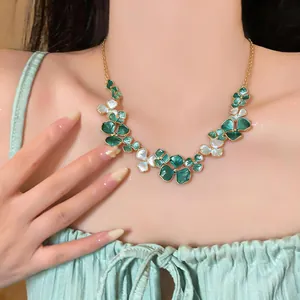 Close-up of a French minimalist gold necklace with green and white flowers on a model