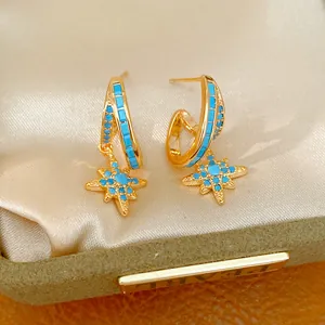 Detailed shot of gold hoop earrings with turquoise starburst charms in a jewelry box