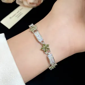 Détail d'un bracelet avec fleurs vert olive et zircons rectangulaires sur le poignet