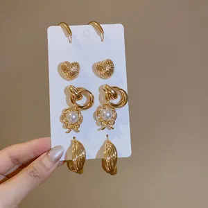 Detailed macro view of a gold-toned earring set featuring pearls and retro heart designs
