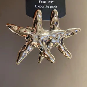Detailansicht der silbernen Seestern-Ohrringe mit glänzender, zerknitterter Metalloptik