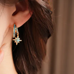 Close-up view of elegant gold double-layered star drop earrings with blue stones