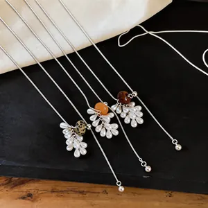 Detailed view of tiger eye and pearl grape cluster pendant necklaces on a black surface