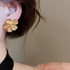 Macro detail view of a vintage golden flower metal stud earring on a female model's ear
