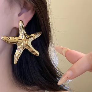 Detailansicht eines großen metallischen goldenen Seestern-Ohrrings mit glänzender Textur