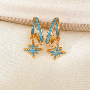 Macro view of elegant double-layered gold star earrings with vibrant turquoise blue stones