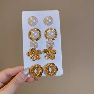 Detailed macro shot of vintage-style gold metal and pearl earring set on a display card.