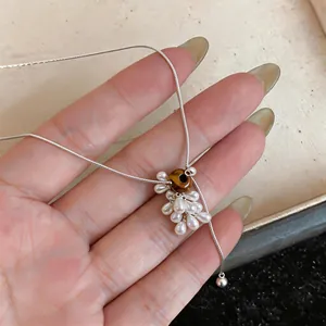 Close-up detail of the tiger eye bead and pearl grape cluster pendant on a silver necklace