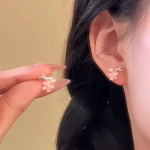 Détail de boucles d'oreilles fleur en pierre œil de chat rose portées à l'oreille
