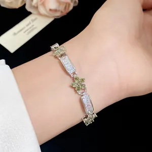 Détail d'un élégant bracelet avec des fleurs en zircone vertes et blanches au poignet