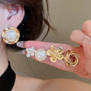 Close-up of vintage gold metal earring set with elegant pearl studs and floral designs.
