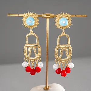 Vintage gold padlock tassel earrings with red beads and blue sunburst stud details.
