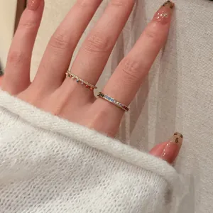 Detailed view of 18k gold plated rings with rainbow stones and charms on a hand.