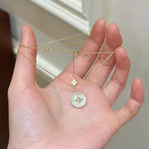 Elegant gold-toned necklace featuring a circular starburst zircon pendant held in hand