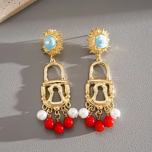 Detailed macro view of vintage gold lock earrings featuring pearl and red droplet tassel accents