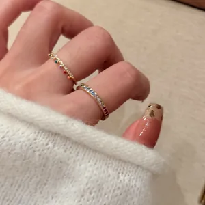 Detailed view of 18k gold-plated rings with rainbow stones and colorful beads on a hand