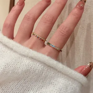 Close-up of 18k gold plated colorful rings worn on finger with cozy knit sweater