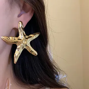 Detailansicht eines großen, gehämmerten Seestern-Ohrrings aus Gold, elegant am Ohr getragen
