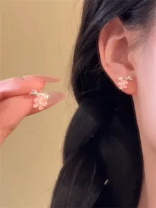 Gros plan de délicates boucles d'oreilles fleurs en œil de chat rose sur l'oreille