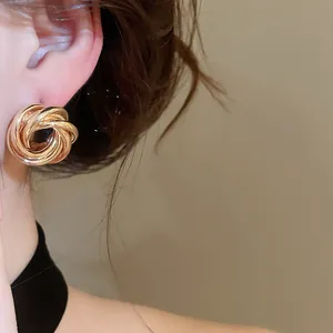 Close-up of vintage gold woven metal stud earrings on ear showing elegant texture and finish.