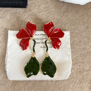 Detail showing vibrant red enamel flower earrings with green polka dot leaf drops