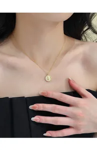 Detailed view of a gold-plated round pendant necklace with star motif on model's neck