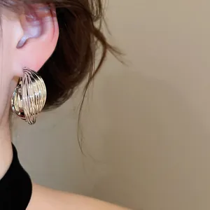Detailed view of elegant silver metallic twisted multi-layer stud earrings on a model's ear