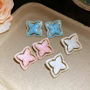 Detail view of vintage style enamel star flower earrings in blue, pink, and white