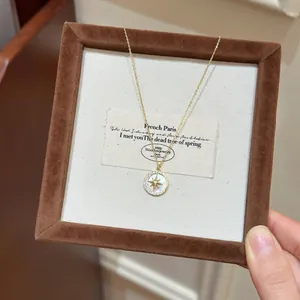 Detailed view of a gold star pendant necklace with white resin inlay and zircon frame.