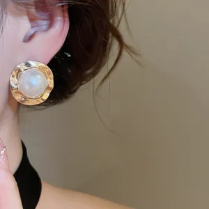 Elegant gold vintage metal earring with pearl center shown worn on ear model detail