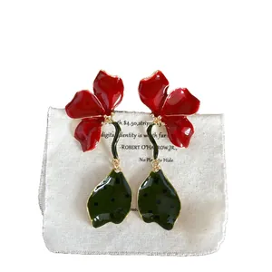 Artistic red enamel flower dangle earrings with green spotted leaf pendants.